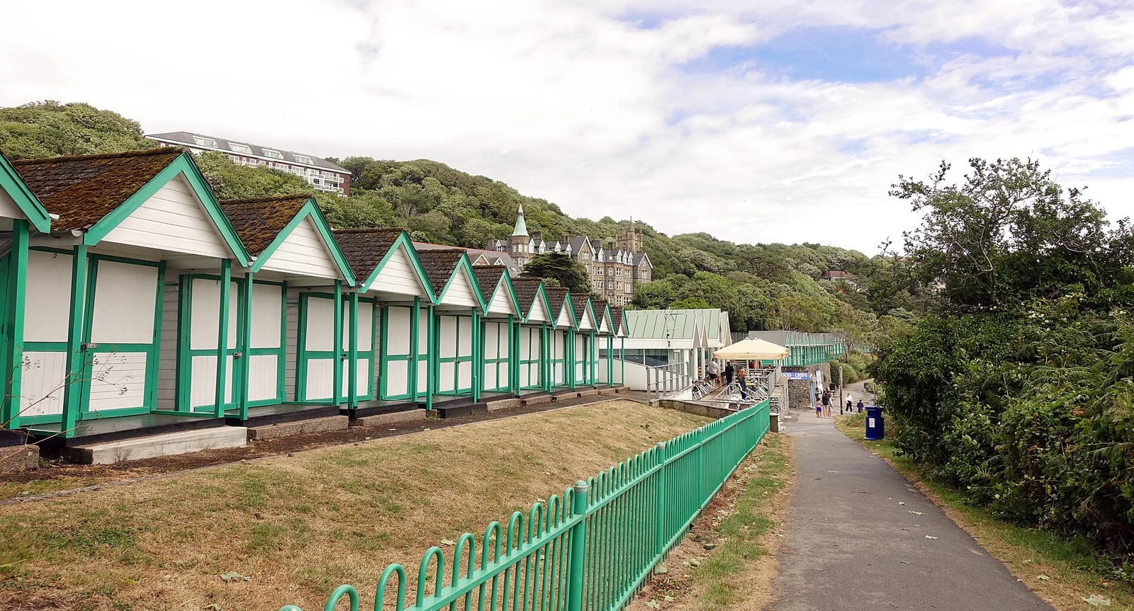 Die grün-weißen Strandhütten und die sandige Bucht der Langland Bay